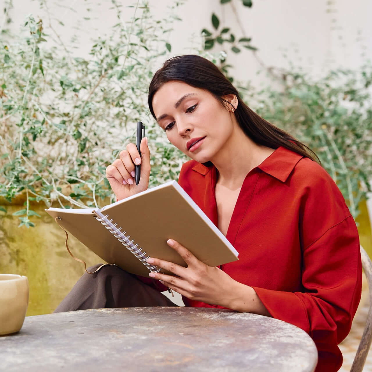mujer escribiendo en libreta con boligrafo metalico negro premium northplanner en ambiente natural